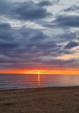 Il s'agit d'un couché de soleil orange sur un plage où l'on peut voir le sable et le bord de mer en fin de journée, le ciel est couvert de nuages épais et bleutés. Il s'agit d'un couché de soleil orange sur un plage où l'on peut voir le sable et le bord de mer en fin de journée, le ciel est couvert de nuages épais et bleutés.